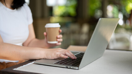 Cropped image of a female freelancer working on her assignment on her laptop at a coffee shop