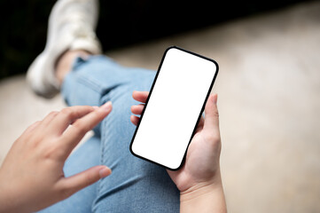 Top view image of a female using her smartphone while sitting indoors.