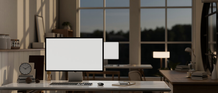 Modern office in the evening with computer white screen mockup on a table