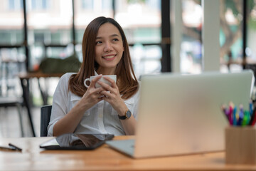 Relaxed young woman having coffee at her desk.