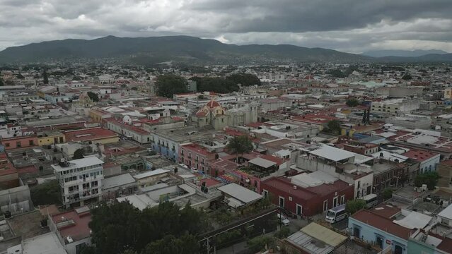 Flyover of low-rise Oaxaca City toward Temple of San Felipe Neri in MX