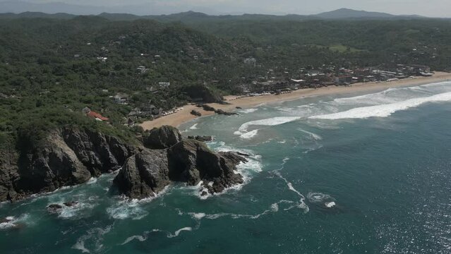 Aerial retreats from hilly tropical beach, clear turquoise sea water