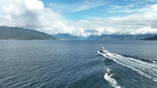 Aerial following tourist motorboat from behind at the Sognefjorden in Norway during summer - Tourists sitting on aft deck during vacation trip to Balestrand and Fjaerland - 60 Fps