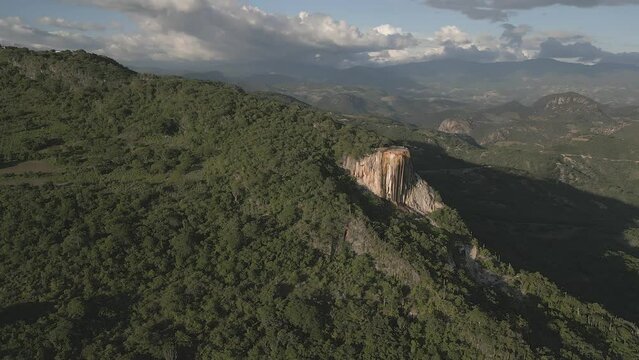 Golden sunset shines on tourists visiting huge flowstone cliff, Mexico