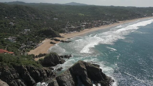 Aerial descends to beautiful Playa Zipolite sand beach in Mazunte, MX