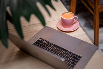 A laptop on the table with a cup of coffee.