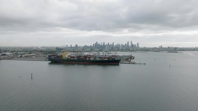 Aerial view of a container ship with the Melbourne city skyline in the distance.