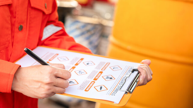 An environmental engineer is using hazardous material checklist form to correct the chemical safety at the factory storage area. Industrial work, photo applied with sunlighting and len flare effect. 