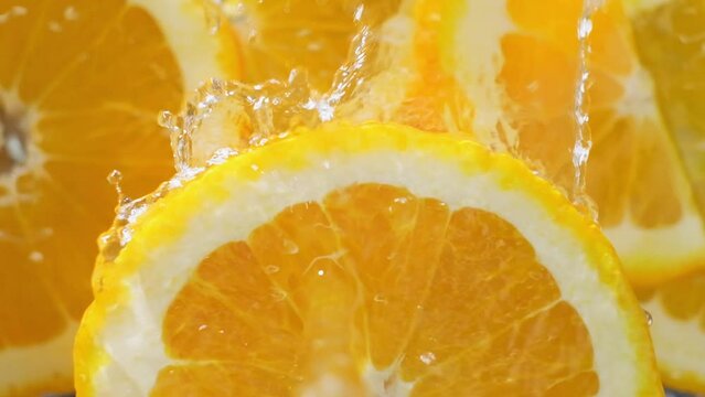 Slow motion shot water falling on top of spinning Orange slice, fresh fruit concept