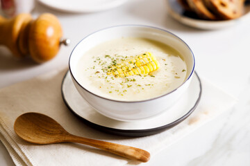 Creamy corn soup in white bowl.