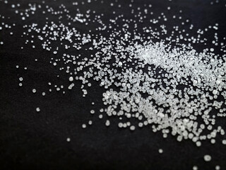A heap of sea salt. A scattering of crystals of salt on a black table or background.