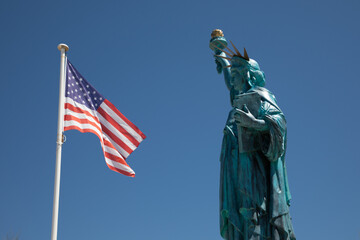 American flag National states flag on wind mat us with copper Statue of Liberty sculpture on Liberty Island in New York Harbor