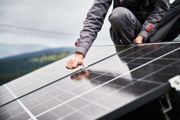 Man engineer mounting photovoltaic solar panels on roof of house. Close up view of technician installing solar module system with help of hex key. Concept of alternative, renewable energy. - Powered by Adobe