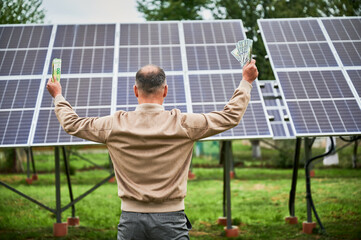 Back view of man happy about profit he got from investing in green energy. Man exulting with huge...