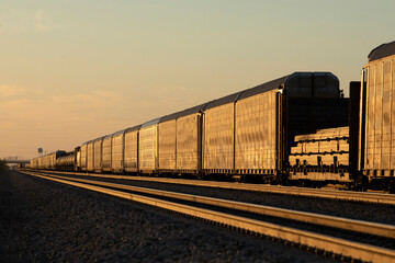 Obraz premium Freight train railcars going away from view at sunset