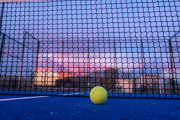 selective focus, a ball on a paddle tennis court at nightfall