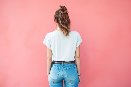 Back view of woman in blank t-shirt and jeans on pink background