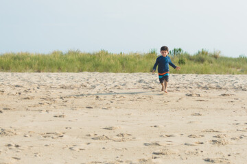 Young boy running on sandy beach. © Cavan