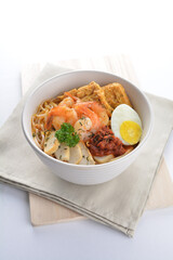 spicy nyonya noodlel malay laksa mee soup with seafood prawn, fish cake, egg, bean curd and chilli sambal thick gravy sauce in bowl on white background asian halal food cuisine menu for cafe design