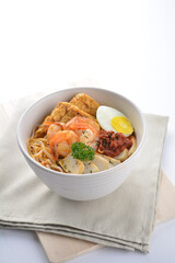 spicy nyonya noodlel malay laksa mee soup with seafood prawn, fish cake, egg, bean curd and chilli sambal thick gravy sauce in bowl on white background asian halal food cuisine menu for cafe design