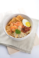 spicy nyonya noodlel malay laksa mee soup with seafood prawn, fish cake, egg, bean curd and chilli sambal thick gravy sauce in bowl on white background asian halal food cuisine menu for cafe design