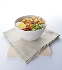 Malay mee rebus noodle with boiled egg, tofu, green chilli, sambal, vegetable, chilli sauce and hot thick spicy gravy soup in bowl on white background asian halal food cuisine menu for cafe design