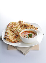 indian baked roti prata canai 2 pieces with spicy chilli curry chicken gravy soup sauce in plate on white background asian halal food cuisine menu for cafe design