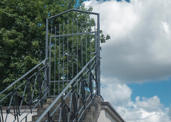 Zamknięta bramka metalowa na końcu schodów na dachu na tle nieba bez ogrodzenia - metafora. © siwyk