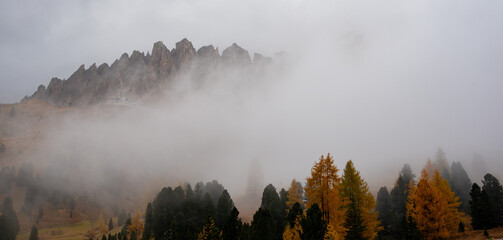 Dolomite mountain peaks covered in fog during sunrise