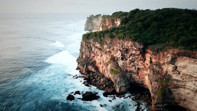 Dreamy big cliffs in the sunset with waves crashing in