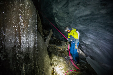 Climber and rescuer on safety rope inside glacial crevasse