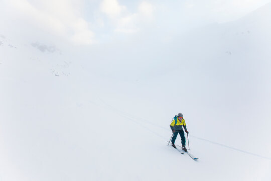 skier skinning up snow covered slope in a cloud