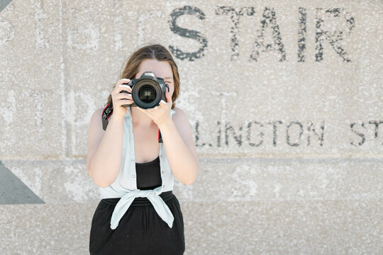 A woman holding a digital camera and taking a photo