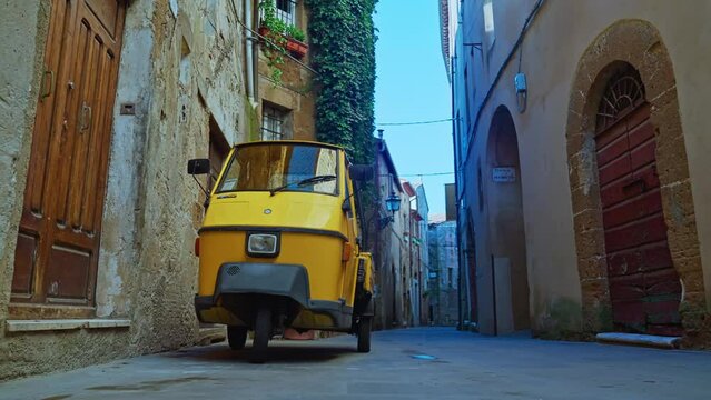 Yellow Piaggio Ape Vehicle - VespaCar Parked On The Narrow Alley In Pitigliano, Italy. - low angle