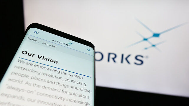 Stuttgart, Germany - 08-08-2023: Mobile phone with webpage of US semiconductor company Skyworks Solutions Inc. on screen in front of logo. Focus on top-left of phone display.