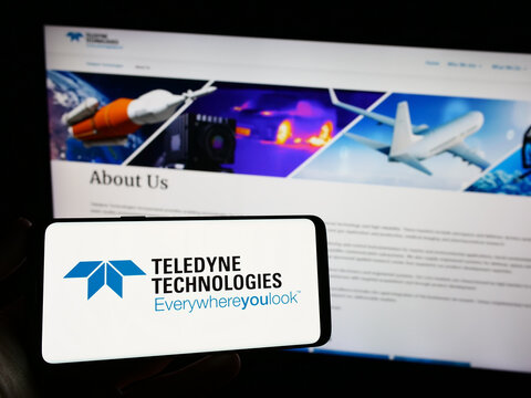 Stuttgart, Germany - 08-09-2023: Person holding smartphone with logo of US company Teledyne Technologies Incorporated on screen in front of website. Focus on phone display.