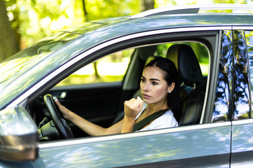 Angry aggressive woman is clenching her fists and threatening from her car.