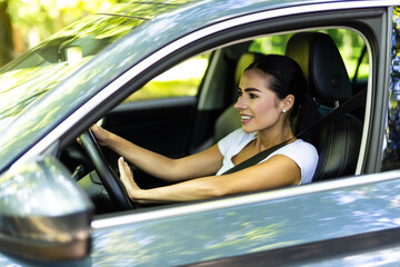 Young woman hand pressing the horn button while driving a car through the road.