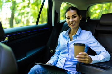 Happy young woman with coffee to go driving her car. Woman sipping a coffee while driving a car.