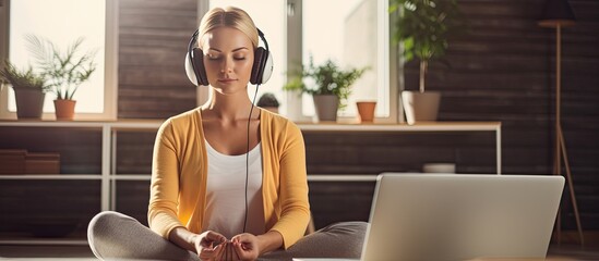 A Caucasian millennial woman using headphones and a laptop for online guided meditation at home © HN Works