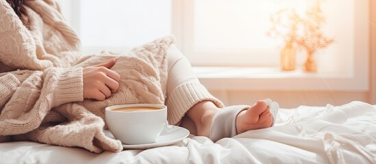 Fototapeta na wymiar Businesswomen working on laptop and drinking coffee on white bed in bedroom conveying a relaxed mood in the winter season Lifestyle concept with space for