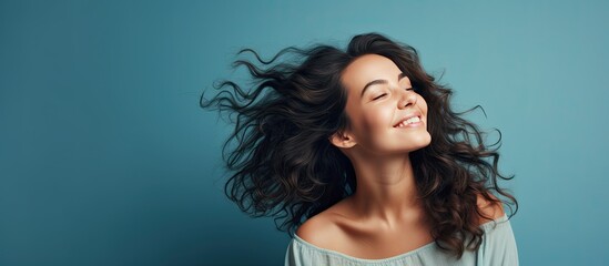 Beautiful young woman in nightwear fixing hair looking away Isolated on blue background Girl s morning routine health and lifestyle concept