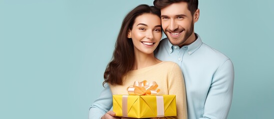 Happy couple friends in casual clothes pose with gift certificate on yellow wall background