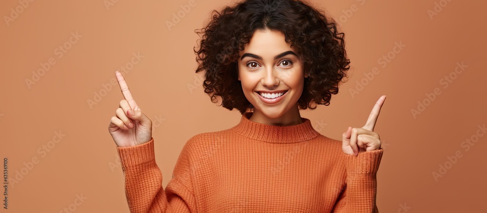 Poster beautiful young woman joyfully pointing to the side and above showcasing an object in the available 
