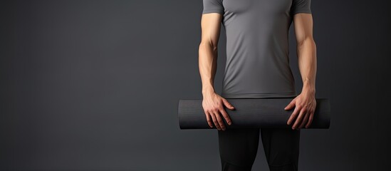 Slim fit model in sportswear holding yoga mat standing isolated on gray background after pilates or...
