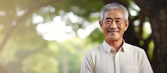 Asian elderly man smiling in park Korean pensioner standing with arms crossed outdoors