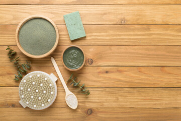 Composition with cosmetic clay and spa products on wooden background, top view