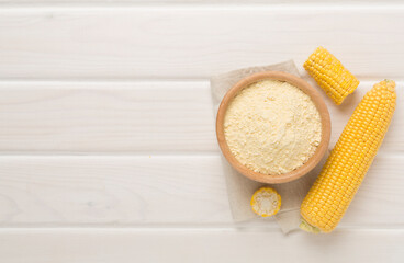 Corn flour with fresh cobs on wooden background, top view