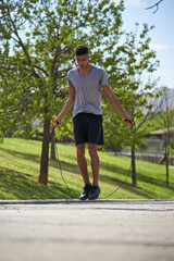 Young man with skipping rope in summer park