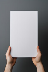 A human hand holding a blank sheet of white paper or card isolated on grey background